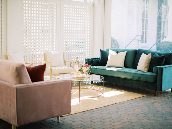 Pink couch, green couch, two linen chairs, gold coffee table, and jute rug 
