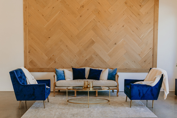 sofa with two blue chairs in front of wood wall
