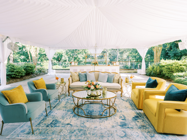 linen sofa with blue and yellow chairs outside under a tent at Umstead Hotel