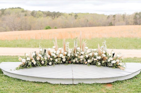 half round stage with florals on top in a field of grass 