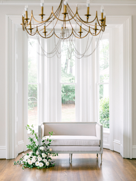 square linen settee with gray trim and legs in front of windows 