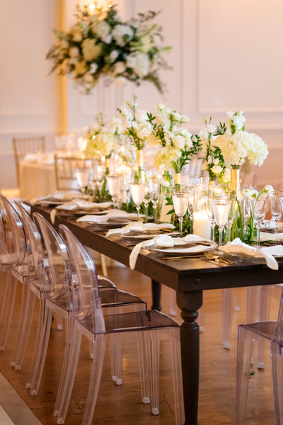 brown wood table with flowers and transparent plastic chairs