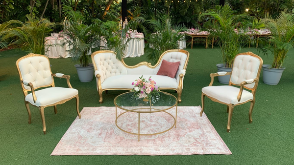 Vintage rectangular pink rug with a vintage lounge set consisting of a vintage loveseat, vintage tufted arm chairs and a round modern coffee table. 