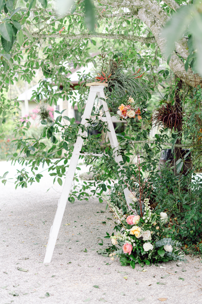 White distressed wood ladder decorated with floral grass decor outdoors