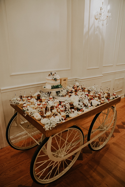 Vintage wood indian cart with white and black accents with desserts on top of it. 