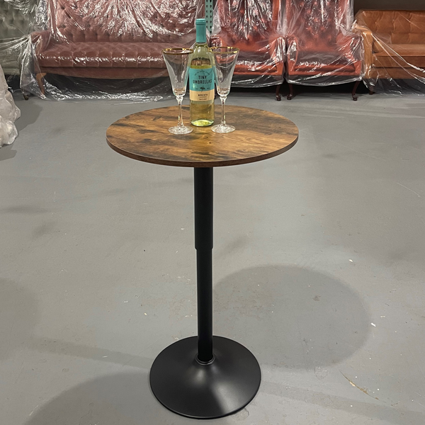 Modern black metal round high and low cocktail table indoors with glassesand a bottle of wine on it.