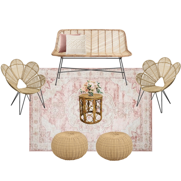 lounge set with rattan boho loveseat with a rattan boho coffee table with rattan boho floral shaped chairs on each side of the coffee table on a pink patterned rug and rattan floor pillows on the edge of it.