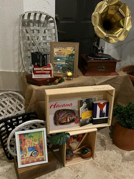 Gold and dark wood vintage gramaphone on a small linen table with crates and old relic decor and paintings. 