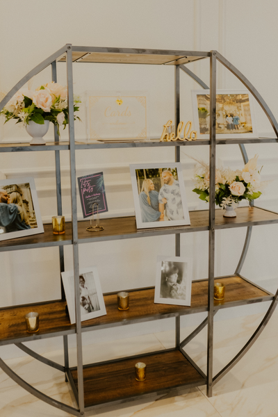 Industrail wood and metal circle shelf with floral vases and picture frames through out it. 