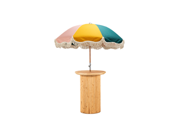 light wood cocktail table with textured base and colorful fringe umbrella