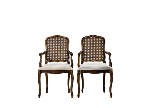 pair of wooden chairs with neutral upholstery and cane back