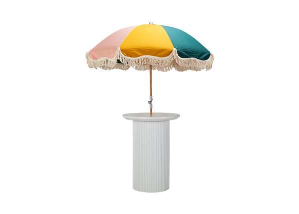 white cocktail table with a ribbed texture and round top with a colorful fringe umbrella 