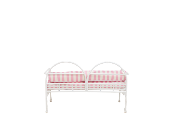 back view of contemporary white curved metal settee rental for events with pink and white striped cushions