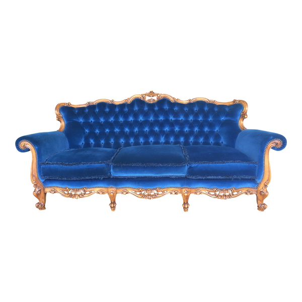 Royal blue velvet tufted sofa with ornate wood detailing for party and event rentals