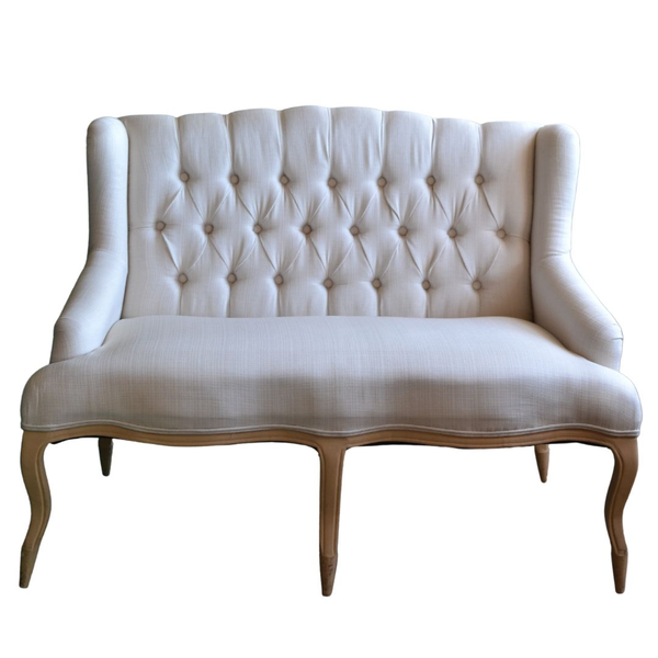 Cream colored settee with tufted details and a shorter back