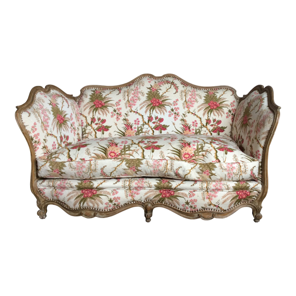 Tropical inspired settee with green and pink floral pattern and extravagant wood detailing