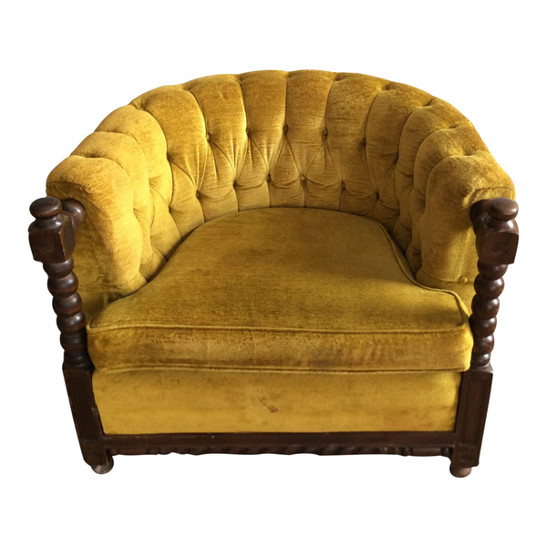 Curved yellow velvet tufted back armchair with ornate spiral wood detailing on arms