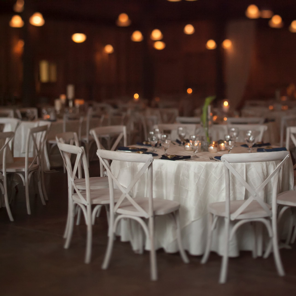 White cross back farm chairs set up for wedding reception inside Carriage House at Goodwood.