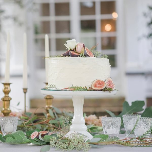 Wedding cake with figs on milk glass cake stand.