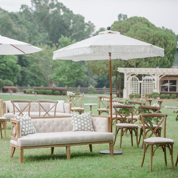 white fringe umbrella set up for an outside ceremony with sofas for social distancing