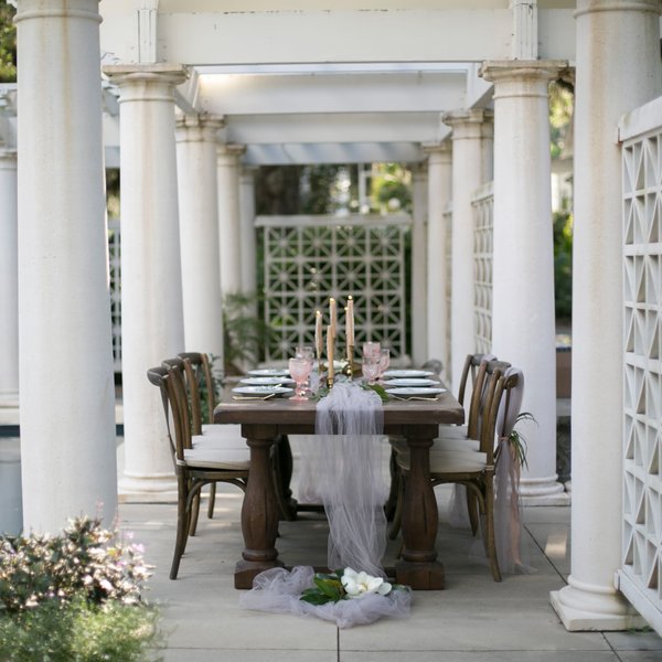 Wood cross back farm chairs with tables under outdoor swimming pool at Goodwood.