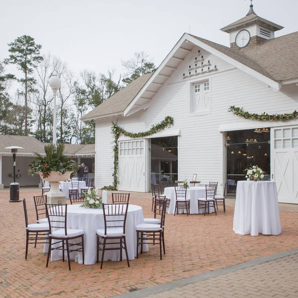 Outside wedding reception with round tables and wedding chairs at Goodwood's Carriage House. 