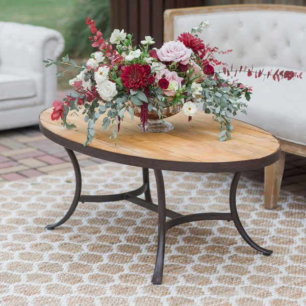 Wood coffee table with boho floral arrangement on top of jute rug for lounge area at Lewiswood Farms wedding.