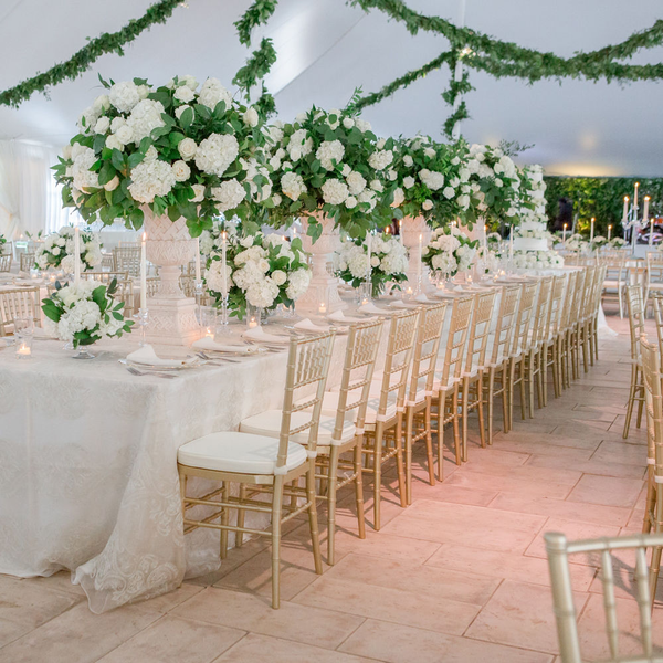 Gold Chiavari wedding chairs at head table with tall floral arrangements inside tent at Gin Creek.