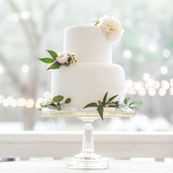 Pedestal glass cake stand with white two tier fondant cake.