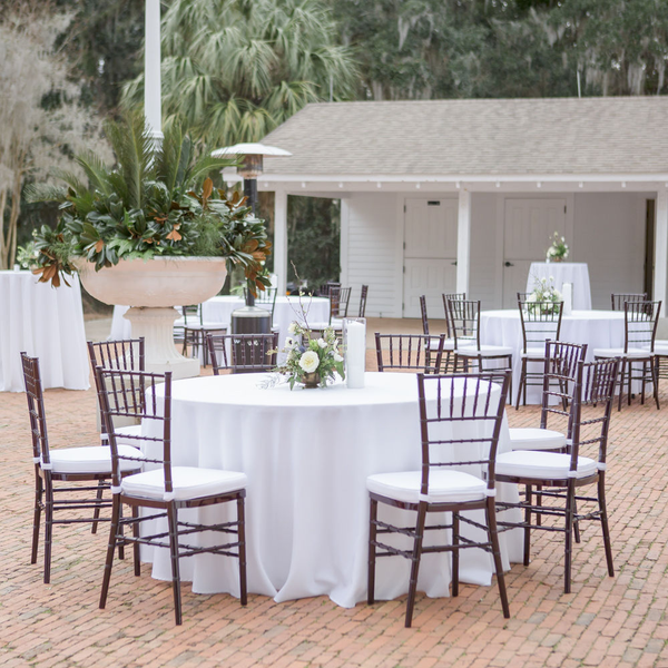 Round white tables with mahogany Chiavari wedding chairs outside Carriage House at Goodwood.