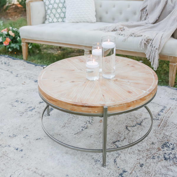 Round wood coffee table with candles in lounge seating for outdoor wedding reception.