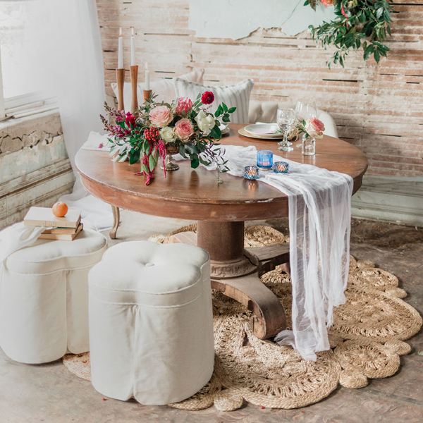 Round pedestal table with stools and round jute rug in abadoned building.