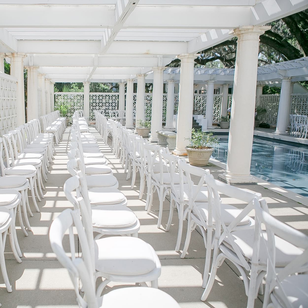 White cross back farm chairs set up for ceremony by pool at Goodwood in Tallahassee, FL.