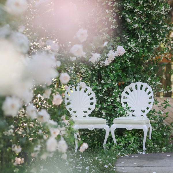 White seashell chairs in pink rose garden for wedding reception at Sienna Lee Gardens.