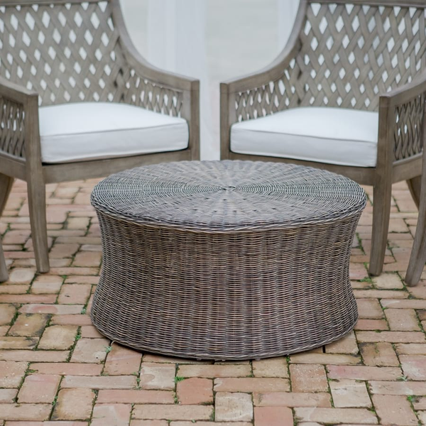 Round wicker coffee table sitting on top of brick patio for wedding lounge area at The Space at Feather Oaks.