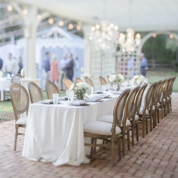 French Cane Back chairs for outside wedding reception under chandeliers at The Space at Feather Oaks.