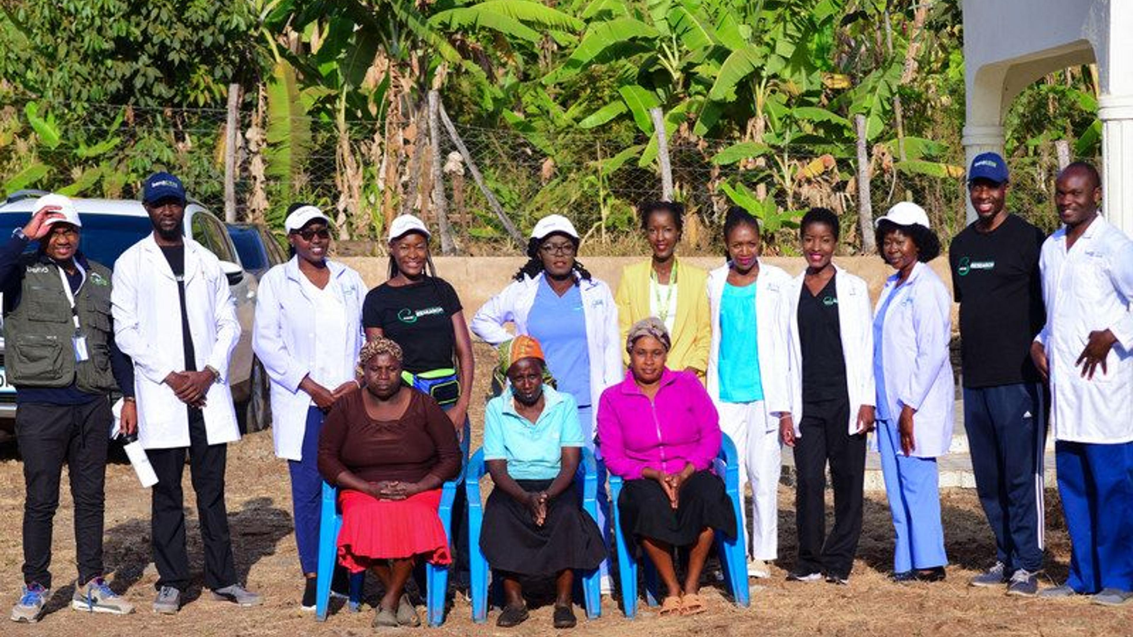 A photo with people posing for a picture. 11 are standing, while three others are seated in front of them, with some donning nursing uniforms.