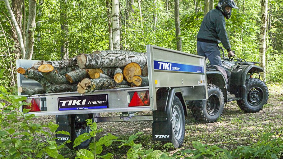 ATV som drar en släpvagn lastad med timmer