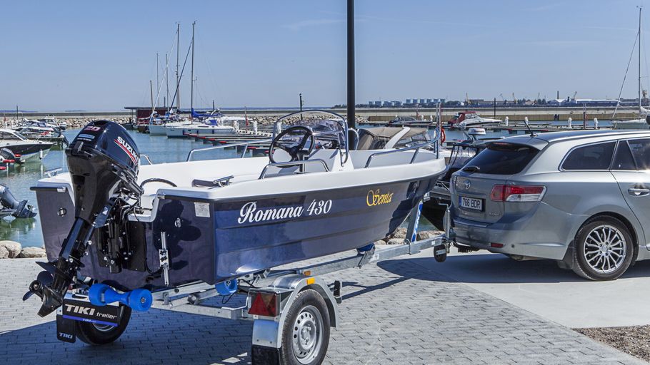 Liten motorbåt på båttrailer bakom personbil