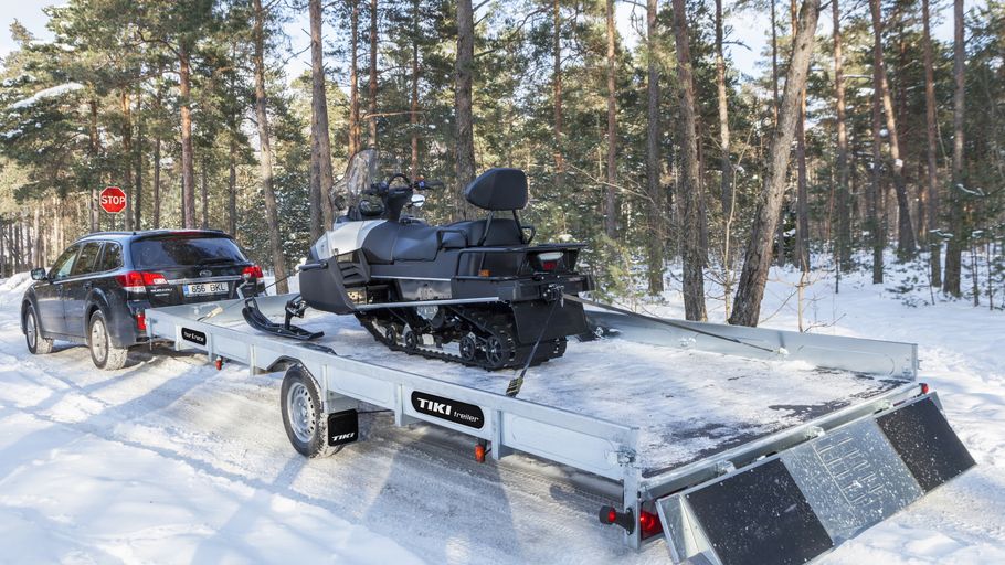 Skotersläp bakom personbil lastad med skoter