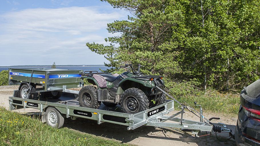 Släpvagn lastad med ATV och mindre släpvagn på skogsväg