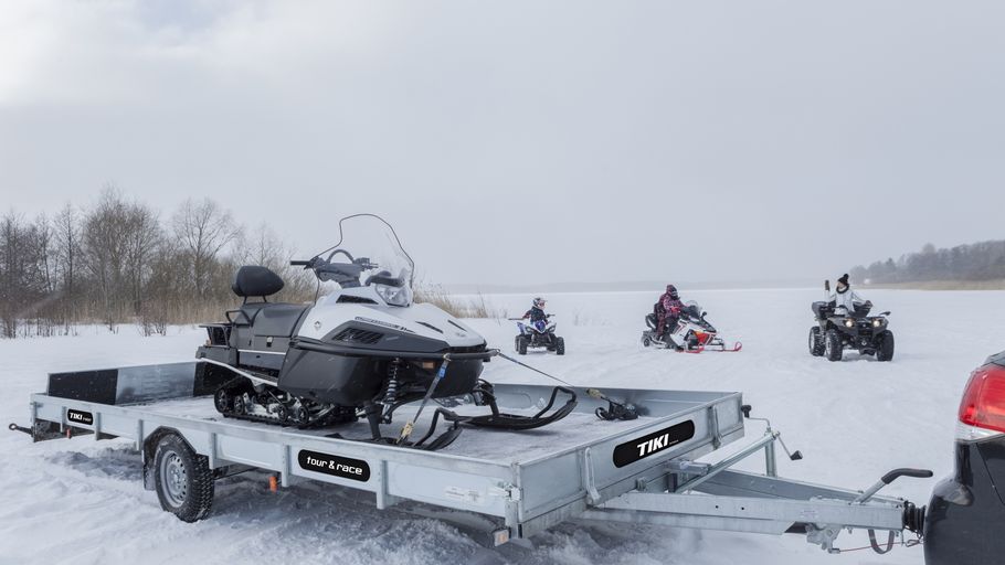 Släpvagn med skoter på sig i snölandskap