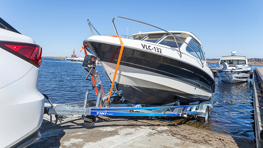 Bil med båttrailer på väg ner i vattnet med båt