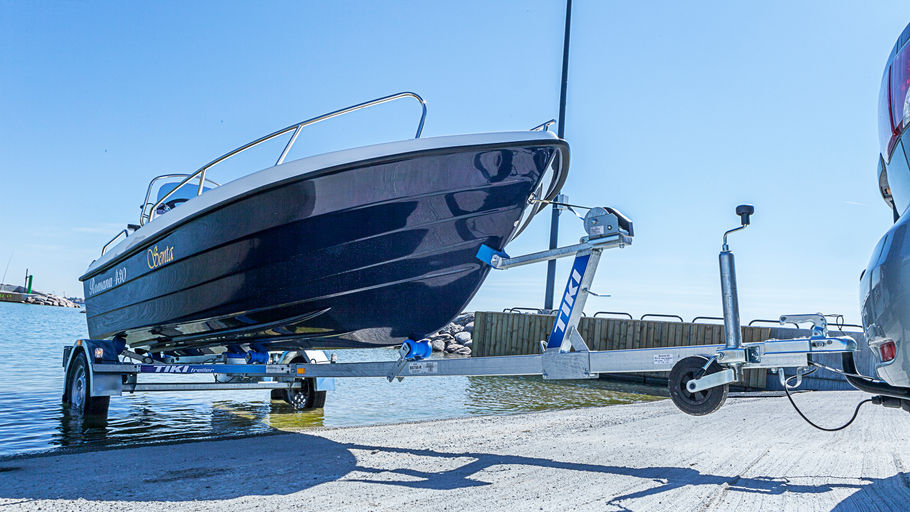 Bil med obromsad båttrailer på väg ner i vattnet med mindre båt