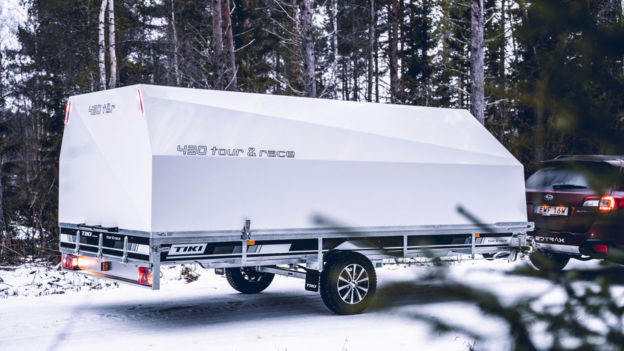 Bil med skotersläp lastad med svart skoter