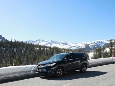 A suv drives near snow-covered mountains.
