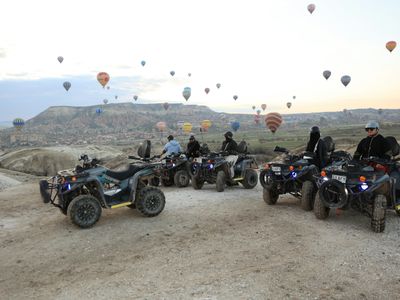 People on atvs with hot air balloons in the sky