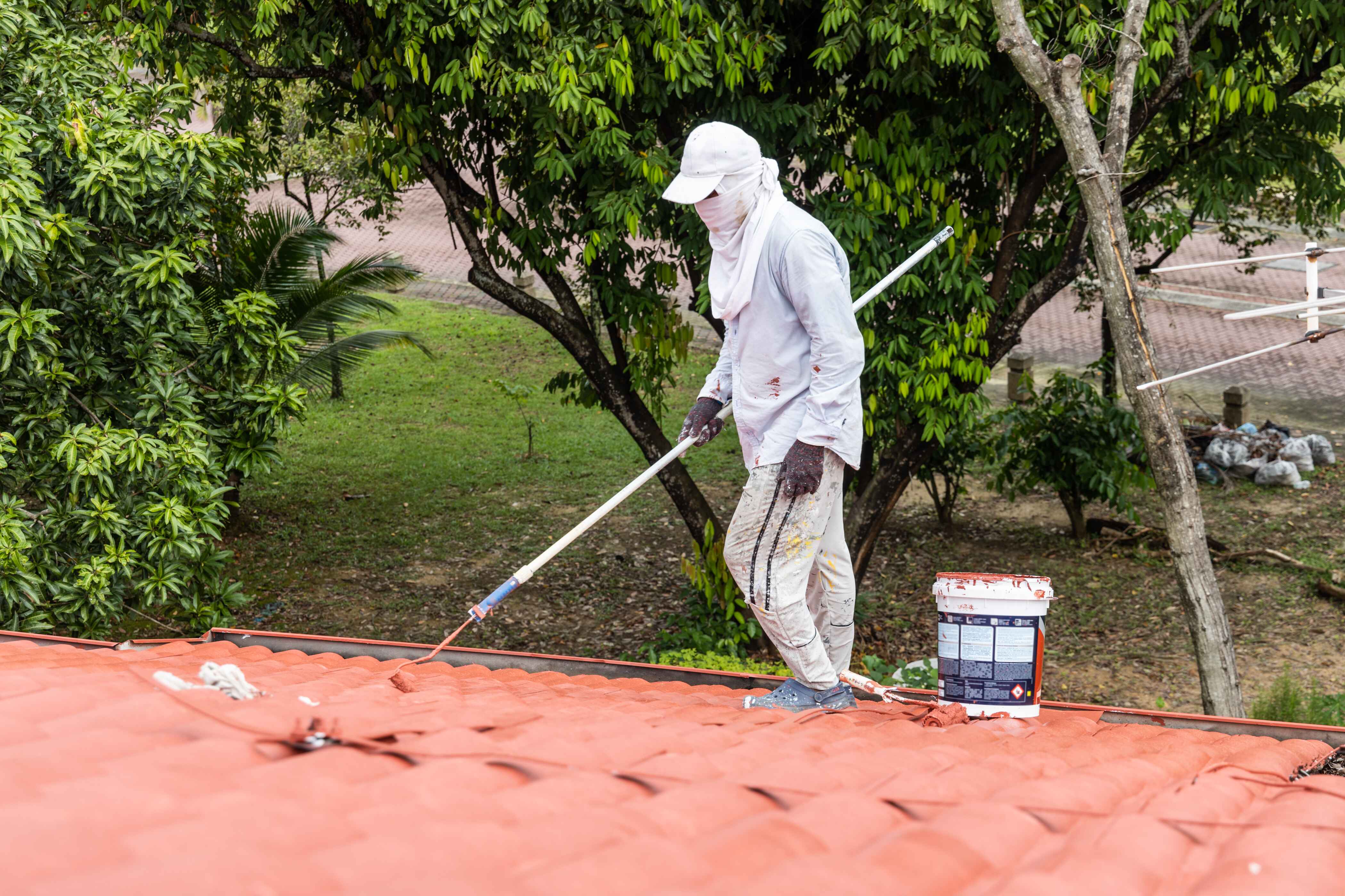 worker-painting-red-rooftop-with-roller-at-residen