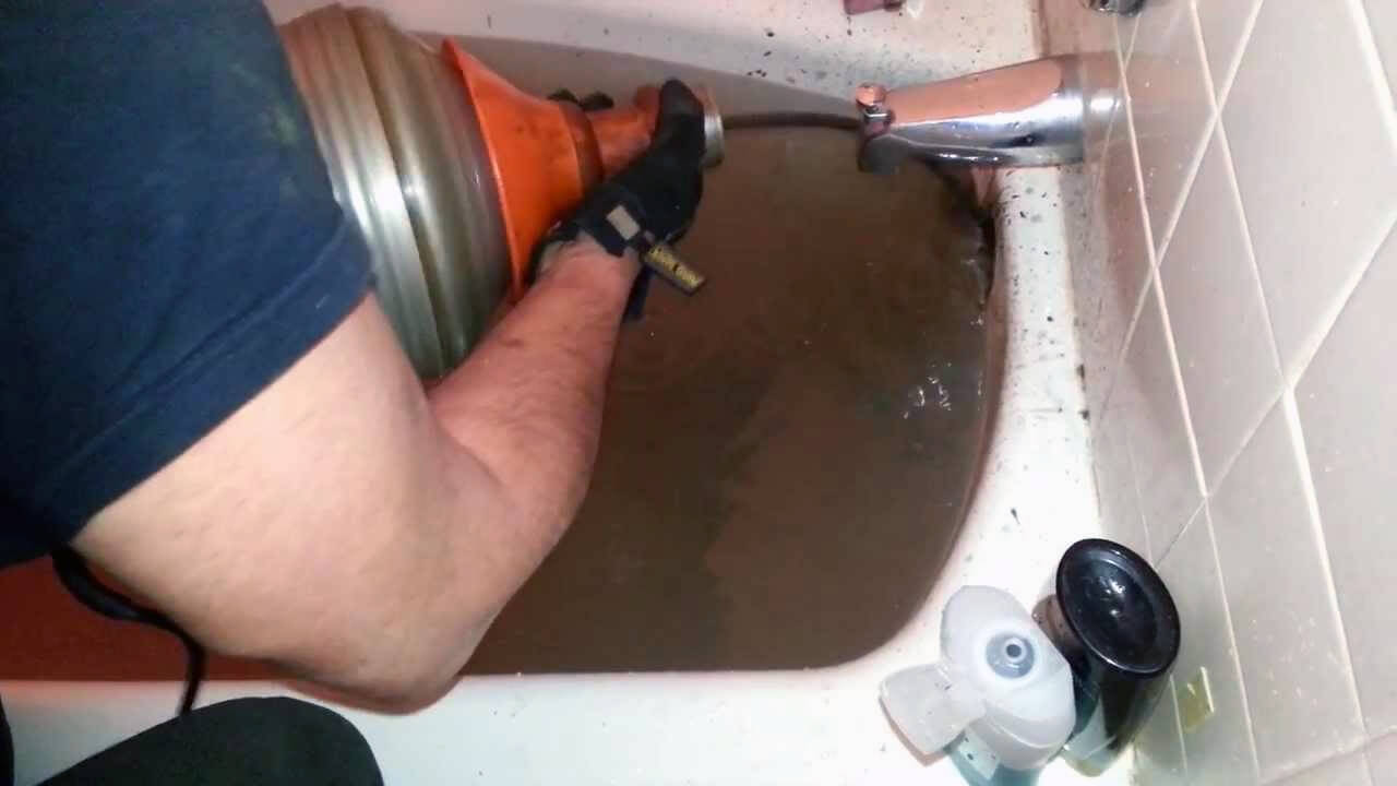 Plumber Using A Drain Snake On Bath Plumber Using A Drain Snake On Bath