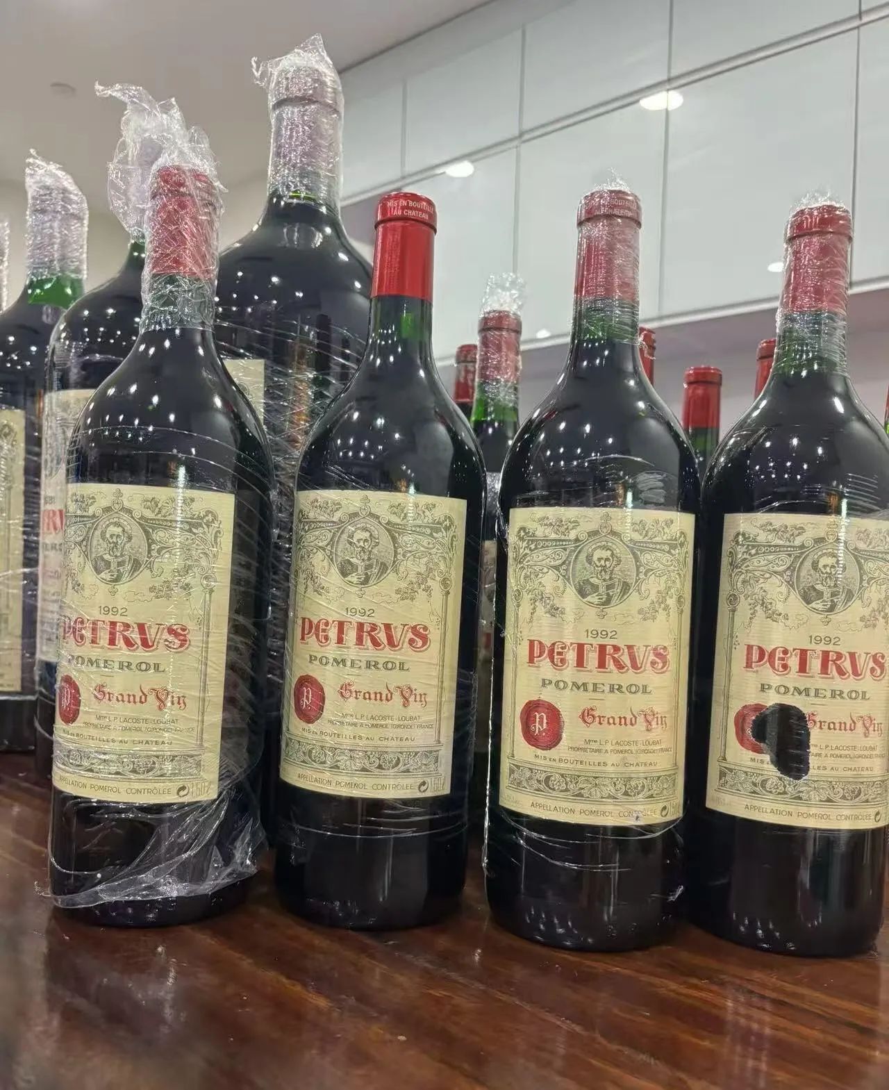 多瓶正標寫有 PETRVS 1992 的紅酒並排，部分酒標有污損與缺口